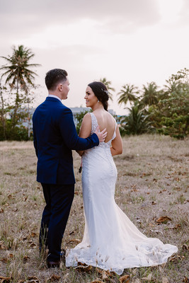 "Pareja de novios caminando en la orilla de la playa al atardecer."