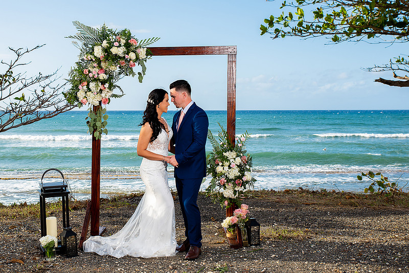 "Pareja de novios caminando en la orilla de la playa al atardecer."