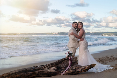 Recién casados posando en la playa con un atardecer dorado en Puerto Rico.
