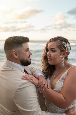 Recién casados posando en la playa con un atardecer dorado en Puerto Rico.
