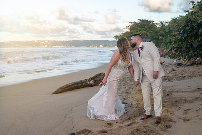 Recién casados posando en la playa con un atardecer dorado en Puerto Rico.
