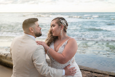 Recién casados posando en la playa con un atardecer dorado en Puerto Rico.
