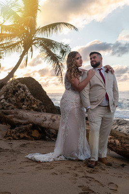 Recién casados posando en la playa con un atardecer dorado en Puerto Rico.
