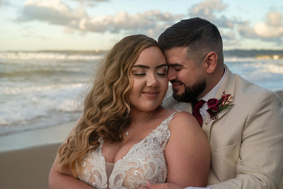 Recién casados posando en la playa con un atardecer dorado en Puerto Rico.
