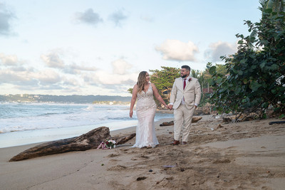 Recién casados posando en la playa con un atardecer dorado en Puerto Rico.
