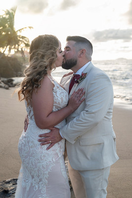 Recién casados posando en la playa con un atardecer dorado en Puerto Rico.

