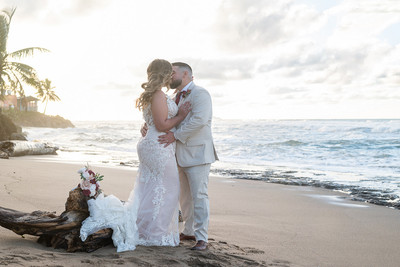 Recién casados posando en la playa con un atardecer dorado en Puerto Rico.
