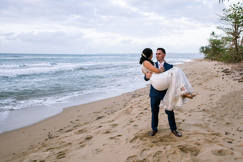 "Pareja de novios caminando en la orilla de la playa al atardecer."