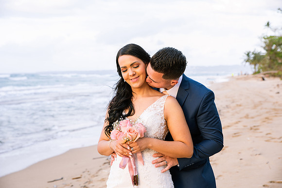 "Pareja de novios caminando en la orilla de la playa al atardecer."