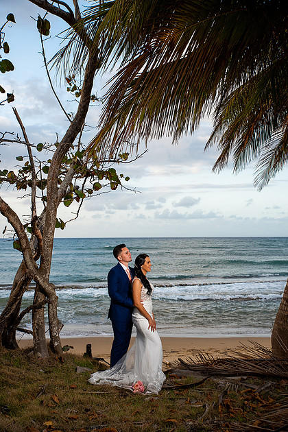 "Pareja de novios caminando en la orilla de la playa al atardecer."
