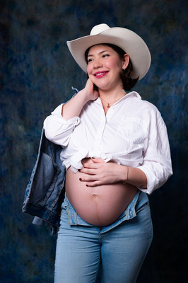  Pareja en espera de su bebé posando en estudio con fondo azul y atuendo vaquero
