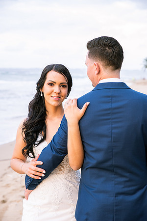 "Pareja de novios caminando en la orilla de la playa al atardecer."