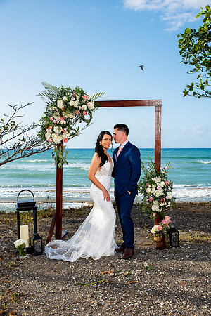 "Pareja de novios caminando en la orilla de la playa al atardecer."